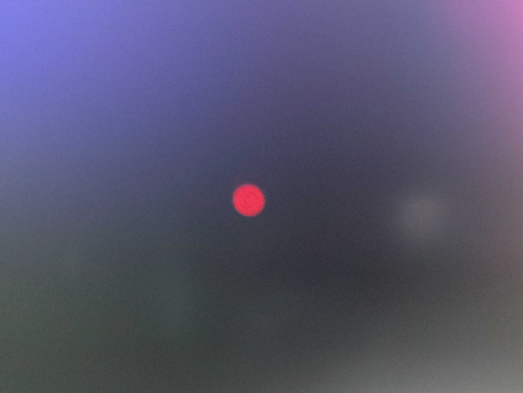A blurry photo of a bright red pixel on a black background.